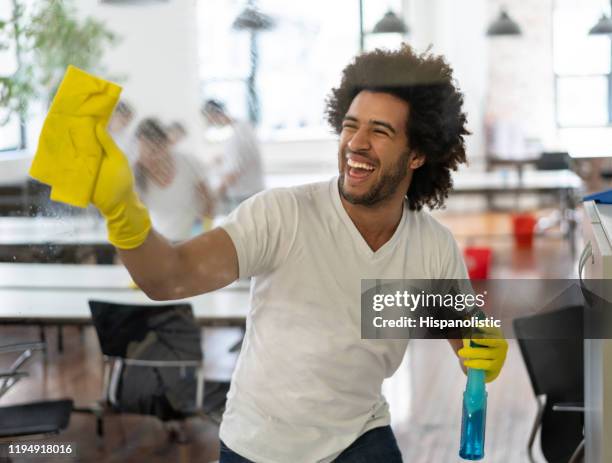 gelukkig jonge schoonmaak aannemer het wassen van een raam zeer vrolijk - office cleaning stockfoto's en -beelden