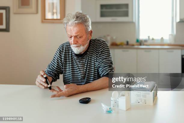 hombre mayor con glucómetro - glycemia fotografías e imágenes de stock