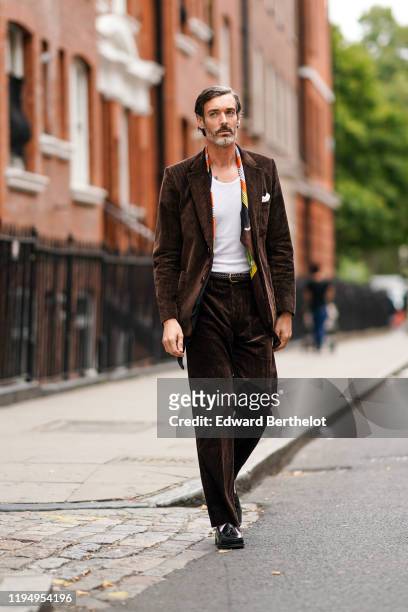 Richard Biedul wears a brown corduroy blazer jacket, a white t-shirt, flare pants, white socks, black leather shoes, outside JW Anderson, during...