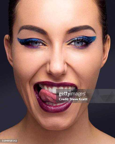 beautiful young woman with full make up sticking out tongue - delineador de ojos fotografías e imágenes de stock