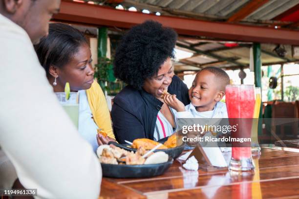 abuela y nieto juegan disfrutar mientras comen su empanada en el típico restaurante colombiano - cali colombia fotografías e imágenes de stock