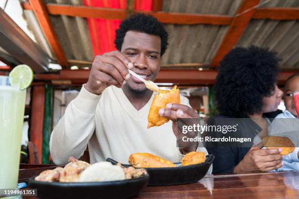 afro papá felizmente comer un delicioso pastel y aplicarlo picante mientras se prepara su mordida - empanada fotografías e imágenes de stock