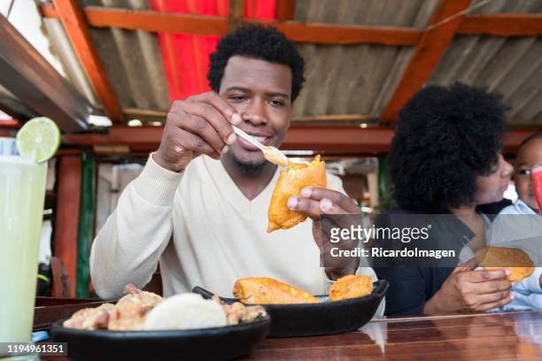 afro dad happily eat a delicious cake and apply it spicy while preparing your bite - cali colombia stock pictures, royalty-free photos & images
