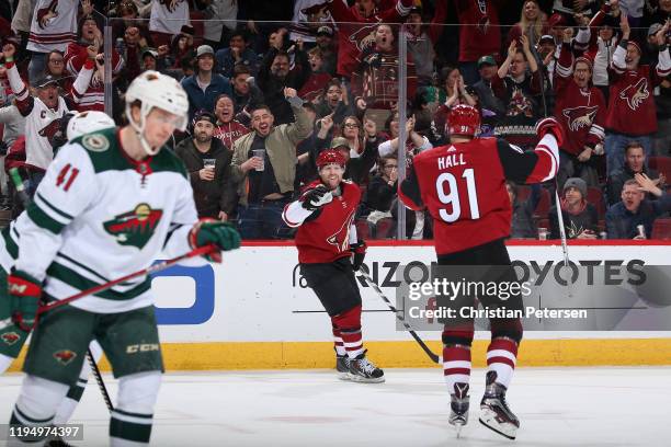 Phil Kessel of the Arizona Coyotes celebrates with Taylor Hall after scoring against the Minnesota Wild during the first period of the NHL game at...