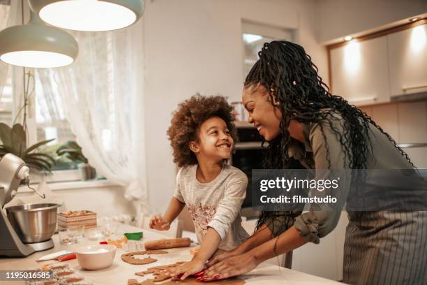 fille effectuant des biscuits de pain d'épice avec la maman - kids cooking christmas photos et images de collection