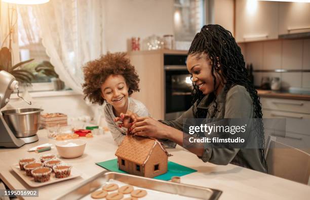 moeder en haar dochter assembleren peperkoek huis - gingerbread house stockfoto's en -beelden