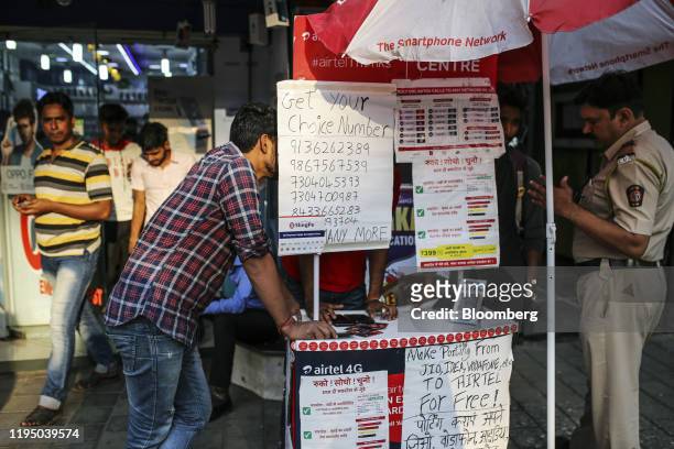 Customer is served at a stall selling Bharti Airtel Ltd. SIM cards outside a mobile phone store in Mumbai, India, on Sunday, Jan. 19, 2020. Telecom...