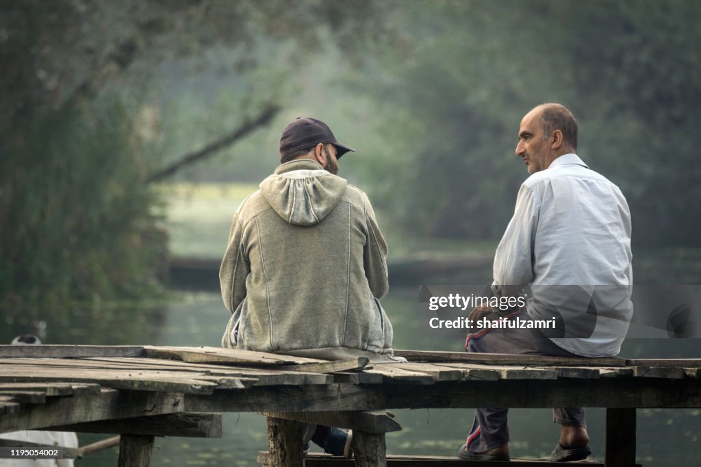 Morning view of traditional floating market with 2 people chatting for future Kashmir.