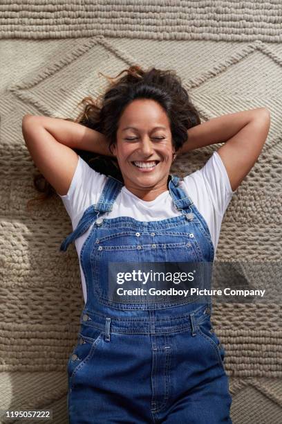 mature woman laughing while lying on her living room floor - hawaiian women weaving stock pictures, royalty-free photos & images