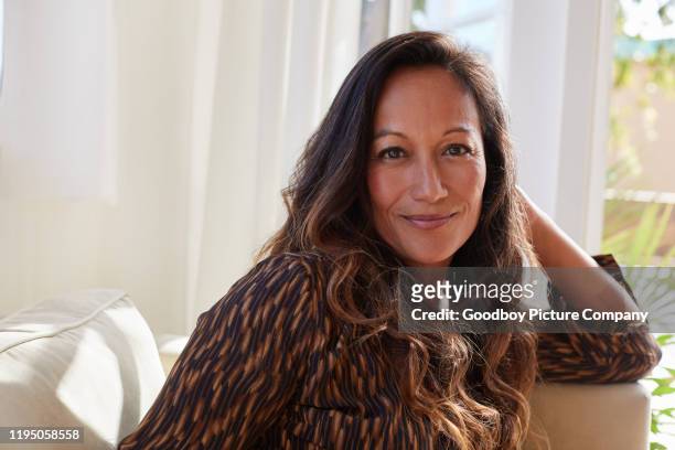 lachende rijpe vrouw ontspannen op haar woonkamer bank - hawaiiaanse etniciteit stockfoto's en -beelden