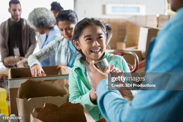 cheerful girl receives food donation while volunteering in food bank - recived stock pictures, royalty-free photos & images