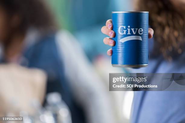 volunteer holds donation can during food drive - canned food drive stock pictures, royalty-free photos & images