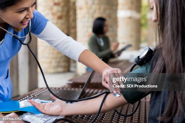 volunteer nurse checks patient's blood pressure - free of charge stock pictures, royalty-free photos & images