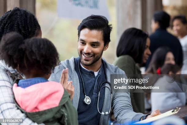 doctor checks patient's vision at outdoor free clinic - community health stock pictures, royalty-free photos & images