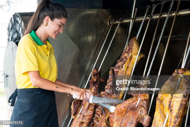 latin woman of approximately 29 years of age employed at a typical meat expert restaurant called mamona called the huge barbecue where the meat is prepared to start slicing it - hot columbian stock pictures, royalty-free photos & images