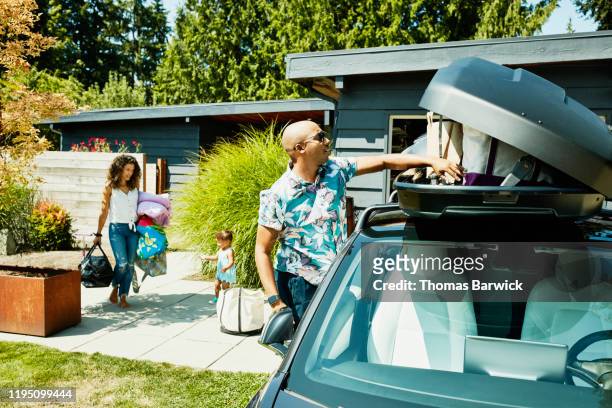 family loading luggage into car top box before road trip - road trip stock pictures, royalty-free photos & images
