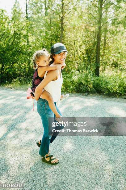 smiling mother giving daughter piggy back ride on summer evening - おんぶ ストックフォトと画像