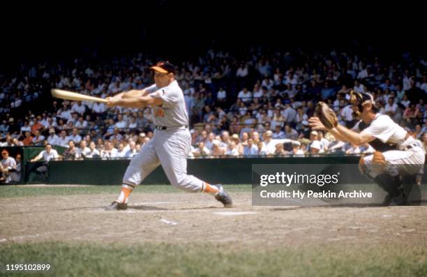 Gene Woodling of the Baltimore Orioles swings at the pitch as catcher Lou Berberet of the Detroit Tigers sets up behind home plate during an MLB game...