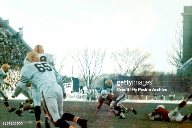 Mel Meyers of the Illinois Fighting Illini runs with the ball as Terry Huxhold and Allan Schoonover of the Wisconsin Badgers go for the tackle during...