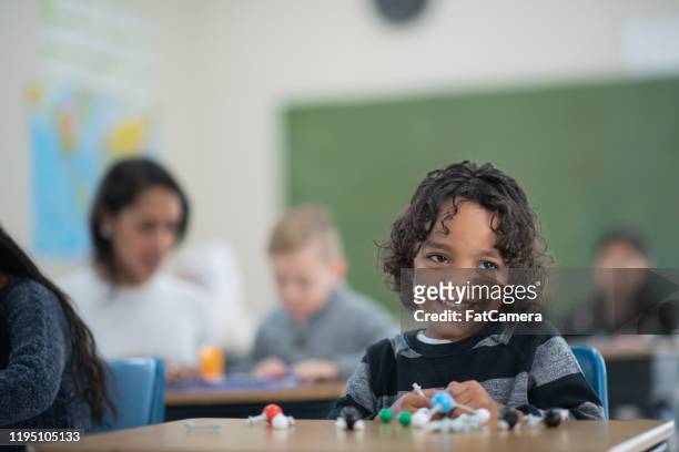 mixed race elementary student working on a science project stock photo - afghani stock pictures, royalty-free photos & images