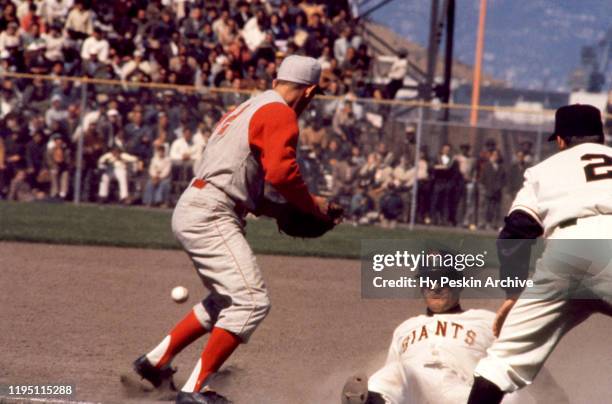 Chuck Hiller of the San Francisco Giants slides into third base after following his coach Salty Parker's instructions to slide as Gene Freese of the...