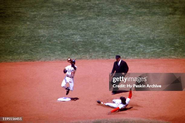 Bill White of the St. Louis Cardinals slides into second base as Nate Oliver of the Los Angeles Dodgers gets ready to tag him out during an MLB game...