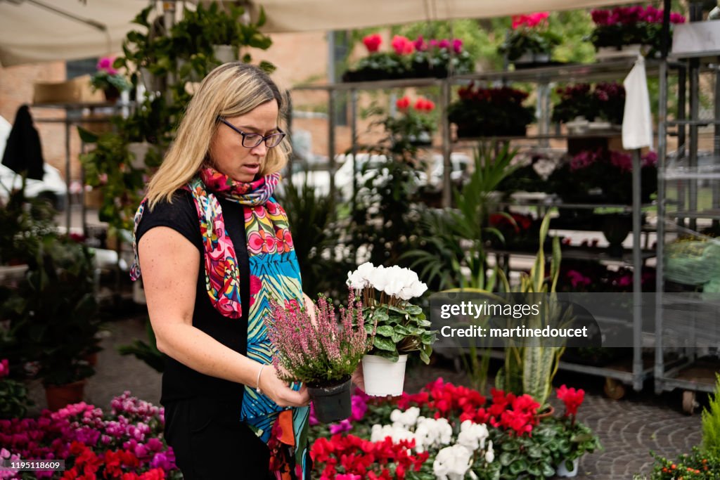 Mature woman shopping in street flower market outdoors.