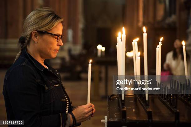 reife frau beleuchtung kerzen in der kirche. - women prayer stock-fotos und bilder
