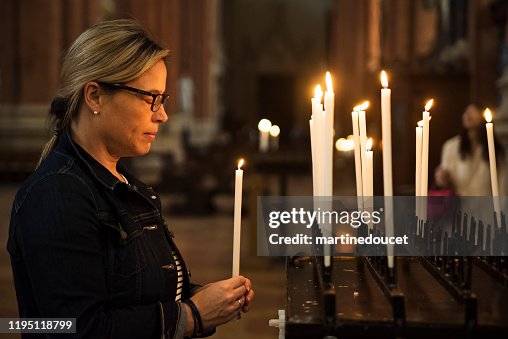 Mujer madura encendiendo velas en la iglesia. Mujer madura encendiendo velas en la iglesia.