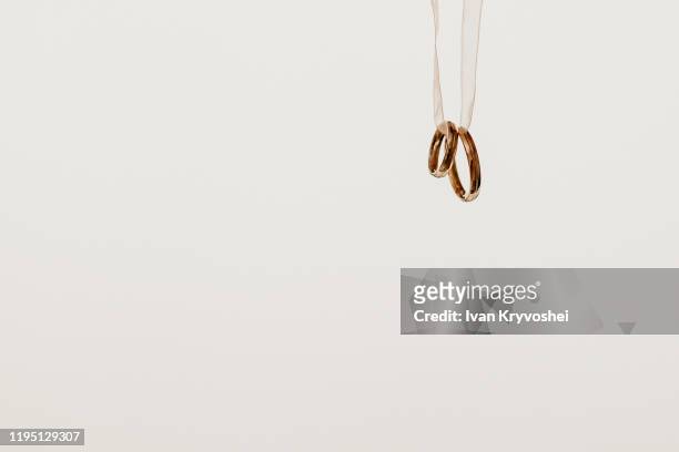 two golden wedding rings hanging on a ribbon, isolated on white background - eheringe stock-fotos und bilder