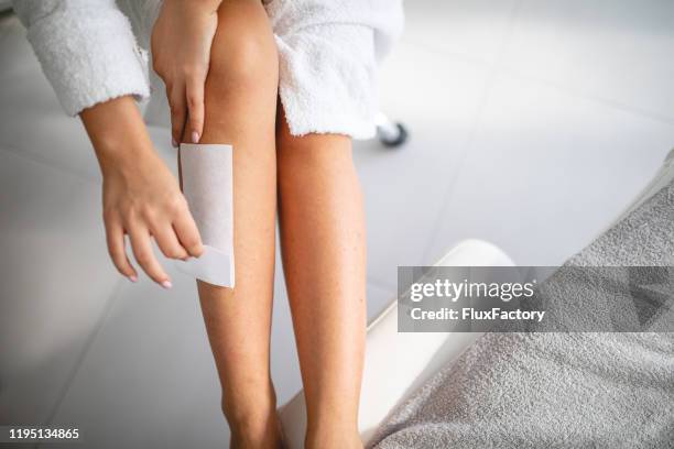 mujer joven depilando piernas - waxing hair removal fotografías e imágenes de stock