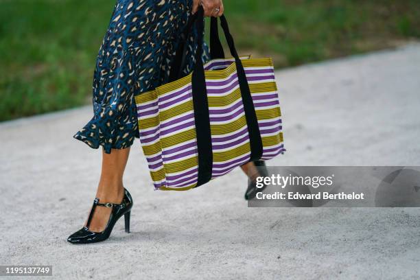Guest wears a deep blue ruffled dress with a white spotted pattern, a pistachio-green, white and purple striped large shopping bag, shiny black...