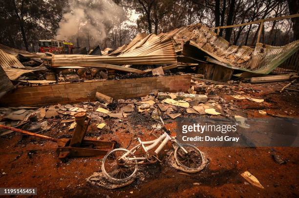 Burnt bicycle lies on the ground in front of a house recently destroyed by bushfires on the outskirts of the town of Bargo on December 21, 2019 in...