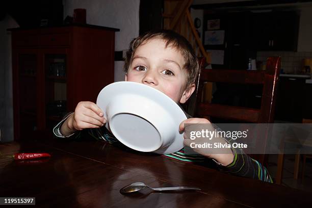 5 year old boy licking his plate - leccare foto e immagini stock