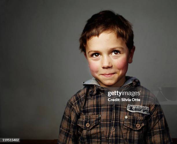 boy smiling shy at camera - child portrait stock-fotos und bilder