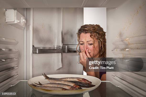 woman finds old fish in the fridge - holding nose stock pictures, royalty-free photos & images