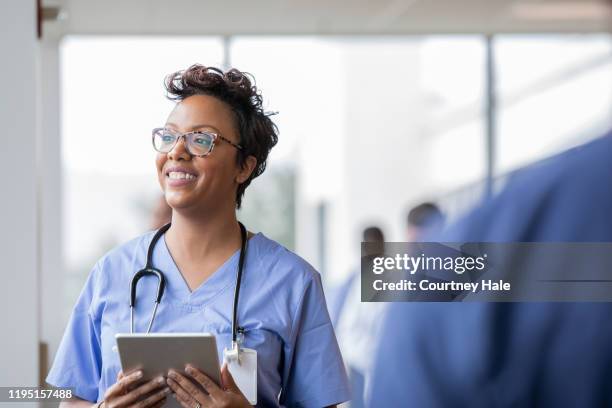 schöne krankenschwester lächelt beim halten digitales tablet - caucasian doctor and nurse using tablet computer stock-fotos und bilder