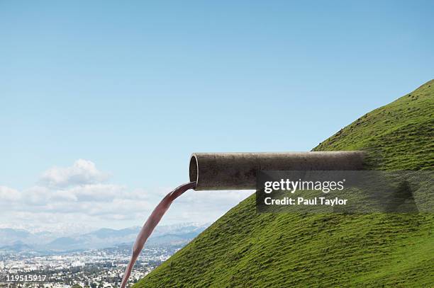 pipe emerging from hillside - riool stockfoto's en -beelden