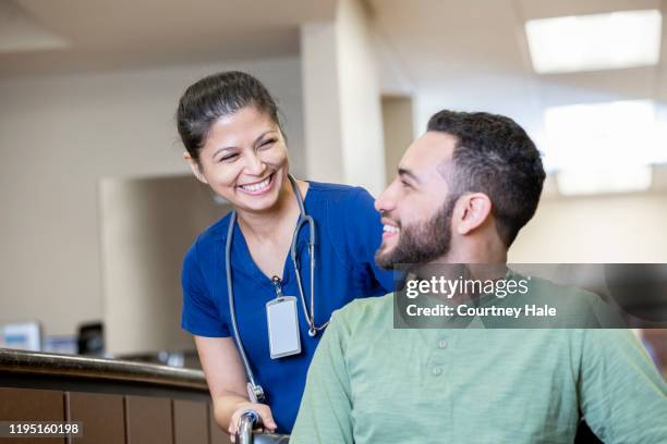 rehabilitation nurse pushes patient in wheelchair - filipino woman smiling stock pictures, royalty-free photos & images