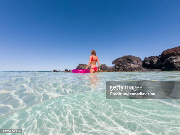 disparo de mujer relajándose con anillo inflable en la playa idílica - see through swimsuit fotografías e imágenes de stock