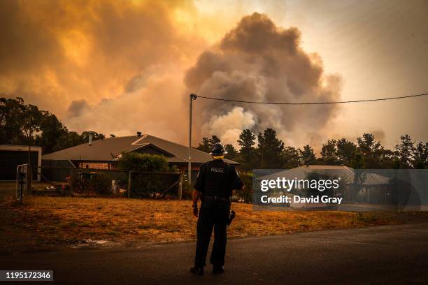 Policeman watches bushfires as they approach homes located on the outskirts of the town of Bargo on December 21, 2019 in Sydney, Australia. A...
