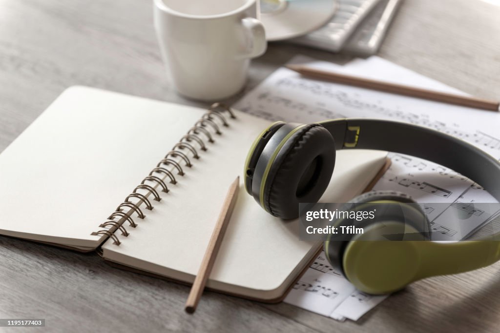 Paper notebook, pencil and earphone with note music paper on the table,Music writer concept, song writer,
