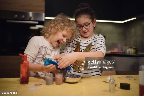little girls enjoying making homemade slime toy - sparkle children stock pictures, royalty-free photos & images