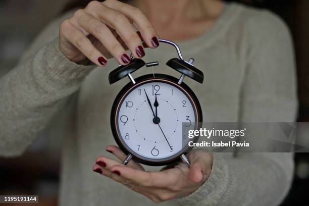 woman holding vintage alarm clock at 12 o'clock. - 12 o'clock stock-fotos und bilder