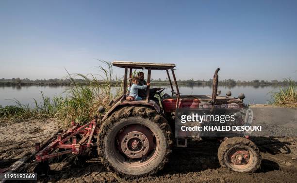 Abdullah el-Hity, a 28-year-old farmer, drives a tractor as his 4-year-old daughter Rodayna sits beside him, while ploughing his field along the bank...