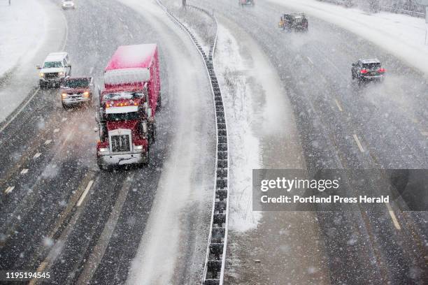 Vehicles travel on Interstate 295 in Portland as heavy, wet snow falls during the morning commute.