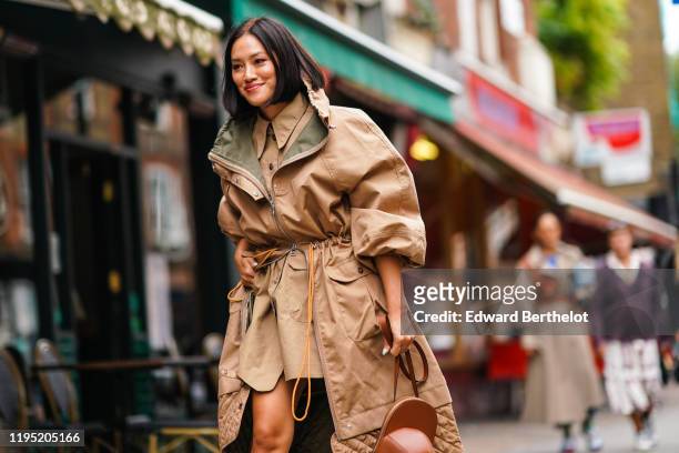 Tiffany Hsu wears a beige coat with khaki inner lining, a shirt, outside JW Anderson, during London Fashion Week September 2019 on September 16, 2019...