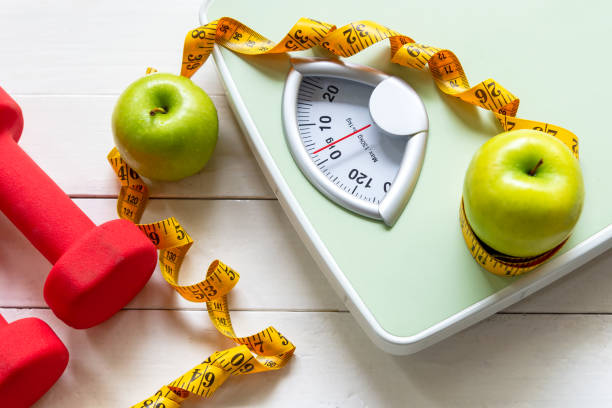 diet and healthy life loss weight concept. green apple and weight scale measure tap with fresh vegetable and sport equipment for women diet slimming. - weight loss stock pictures, royalty-free photos & images