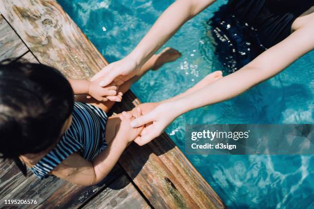 overhead view of cute asian toddler girl enjoying family bonding time with mother and having fun in the swimming pool during summer vacation - family holidays hotel stock pictures, royalty-free photos & images