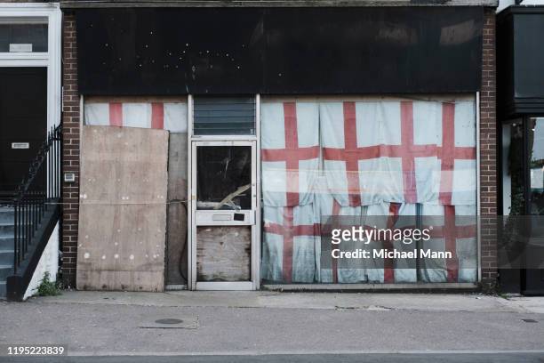 english flags covering abandoned storefront, margate, england - abandoned store stockfoto's en -beelden